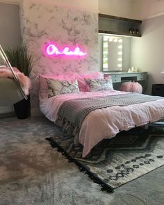 a bed room with a neatly made bed and a neon sign