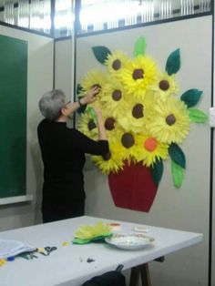 a woman is working on a large paper flower arrangement in front of a blackboard