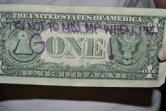 a person holding a one dollar bill with purple writing on the front and back of it