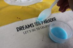 a person is spooning blue liquid out of a container with a white spoon in it