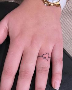 a person's hand with a small heart tattoo on the middle finger and an i love you written across it