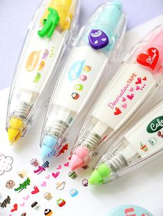 three pens sitting next to each other on top of a white table with stickers