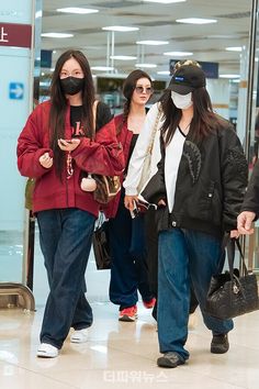 three women wearing masks walking through an airport