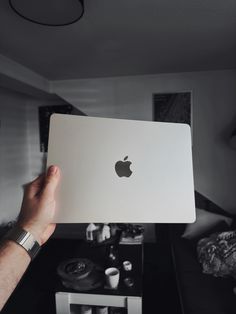 a person holding an apple laptop in their hand