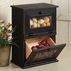 an old fashioned oven is open with some food in it's drawer next to a potted plant