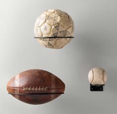 three different types of sports balls hanging from hooks on a wall, one with a football and the other without