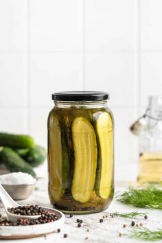 pickles in a jar with spices and seasoning on the table next to them