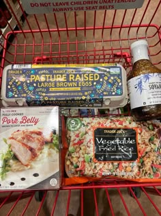 some food is sitting in a red shopping cart and on the shelf next to it