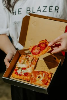 a person is holding a box with pizza in it and one slice has been taken out