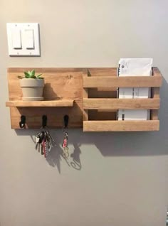 a wall mounted shelf with keys and key hooks on it, next to a light switch