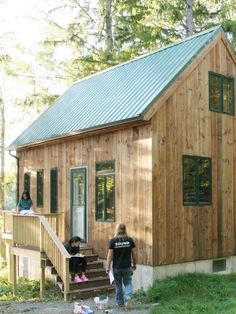 two people are standing in front of a tiny house with stairs leading up to it