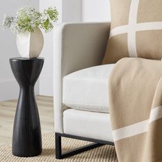 a black and white vase sitting on top of a table next to a chair