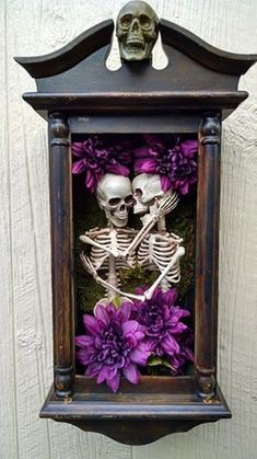 a couple of skeletons sitting in a frame with purple flowers on the outside and inside