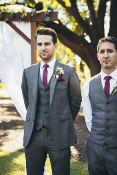 two men in suits standing next to each other under a white cloth covered chute