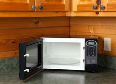 a black and white microwave oven sitting on top of a counter next to wooden cabinets