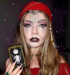 a woman with makeup on her face holding up a small box in front of her face