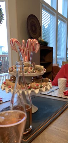 the table is set with candy canes, cookies and hot chocolate in glass vases