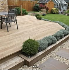 a wooden deck surrounded by plants and gravel