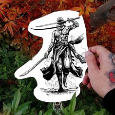 a hand holding up a sticker with a drawing of a samurai on it