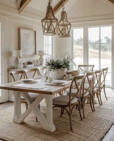 a dining room table and chairs in front of large windows