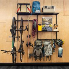 there is a bike hanging on the wall next to some shelves with backpacks and other items