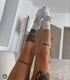 two people with tattoos on their legs sitting on a bed