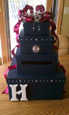 a three tiered blue cake with red ribbon and decorations on it's side