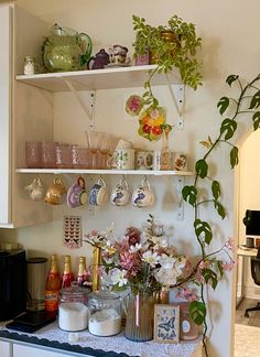 a kitchen counter topped with lots of dishes and vases filled with flowers next to a coffee maker