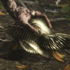 a close up of a person's hand holding an object in front of leaves