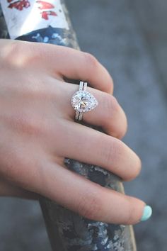 a woman's hand with a ring on her finger and a diamond in the middle