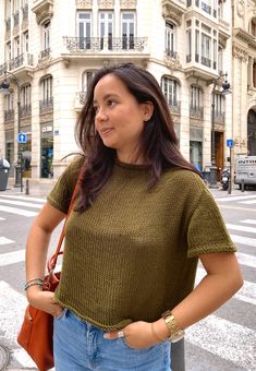 a woman standing in front of a building with her hands on her hips and looking off to the side