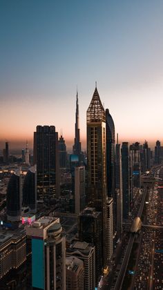 an aerial view of a city at dusk with skyscrapers and cars on the road