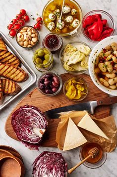 an assortment of food on a cutting board with cheese, olives, and other foods