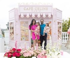 a man and two women standing in front of a pink stand with flowers on it