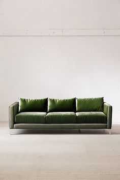 a green couch sitting in front of a white wall