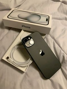 an iphone in its box on top of a bed with the case open and ear buds plugged into it