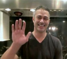 a man standing in front of a stove holding his hand up