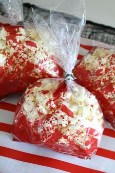 three bags filled with red and white sprinkles on top of a table