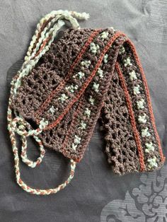 three crocheted brown and white scarfs laying on top of a gray blanket