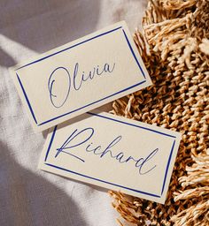 two place cards sitting on top of a pile of dried up corn stalks with the word, ollivia richard written in blue ink