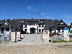 a large white house with two cars parked in front of it and a gated driveway