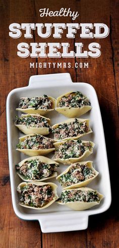 stuffed shells filled with meat and spinach on top of a white plate next to a wooden table