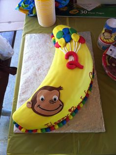 a cake shaped like a banana with a monkey on it's face and balloons attached to the top