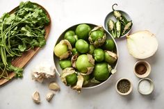 green vegetables are in bowls on a white counter top next to garlic and other ingredients