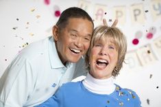 an older couple posing for a photo in front of confetti and streamers