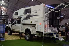 a white truck with a camper attached to it's bed in a tent