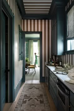 a woman is standing in the doorway of a kitchen with striped walls and flooring