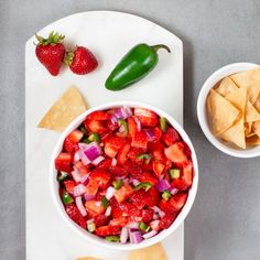 a white bowl filled with fruit and vegetables next to tortilla chips