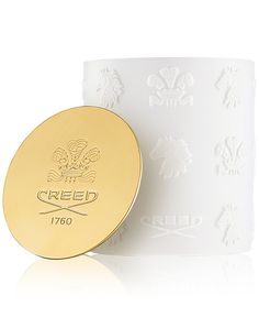 a white candle with a gold lid and the word reed engraved on it's side