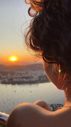 a woman looking out over the water at sunset